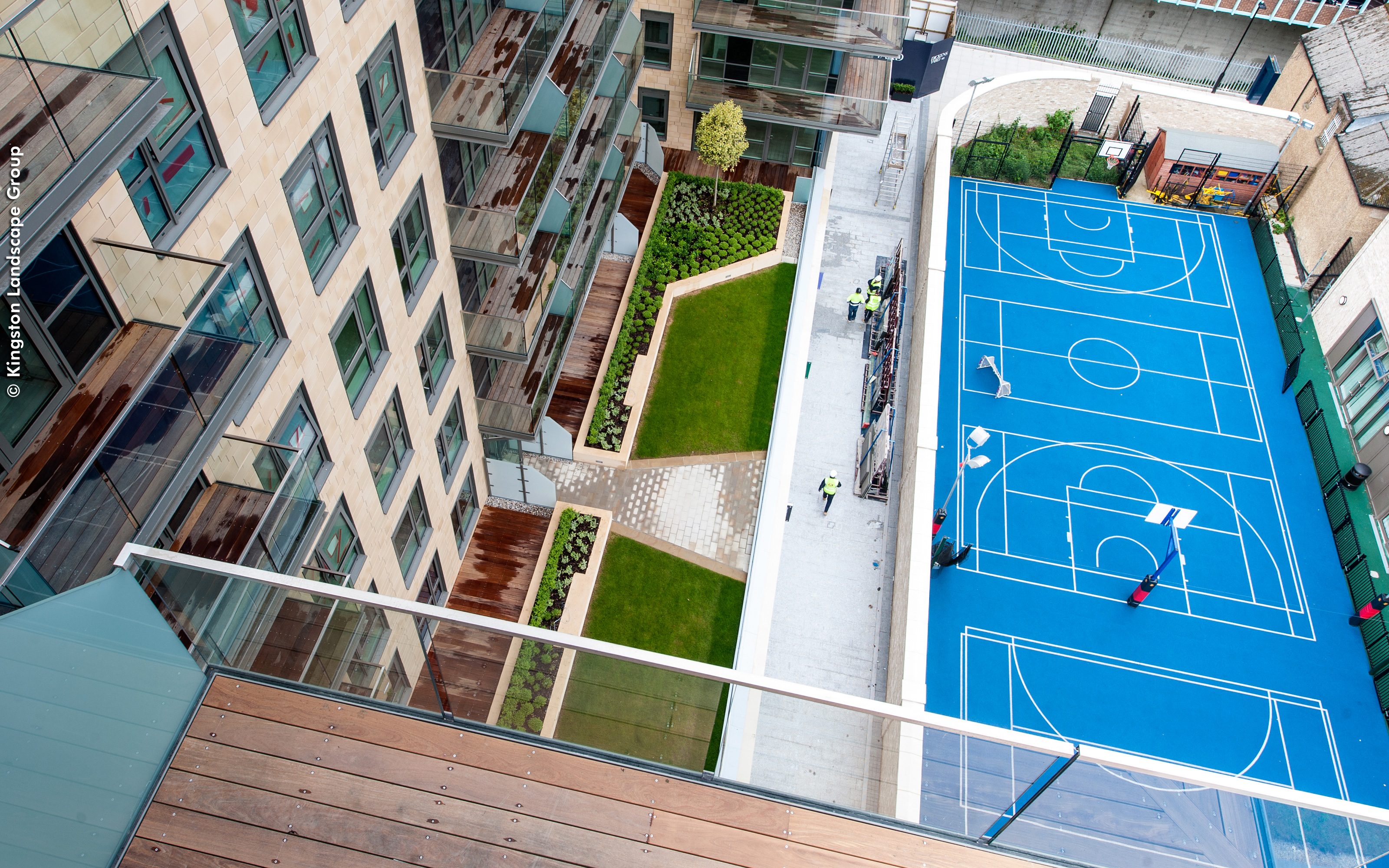 Bird's eye view into a green courtyard and a basketball court